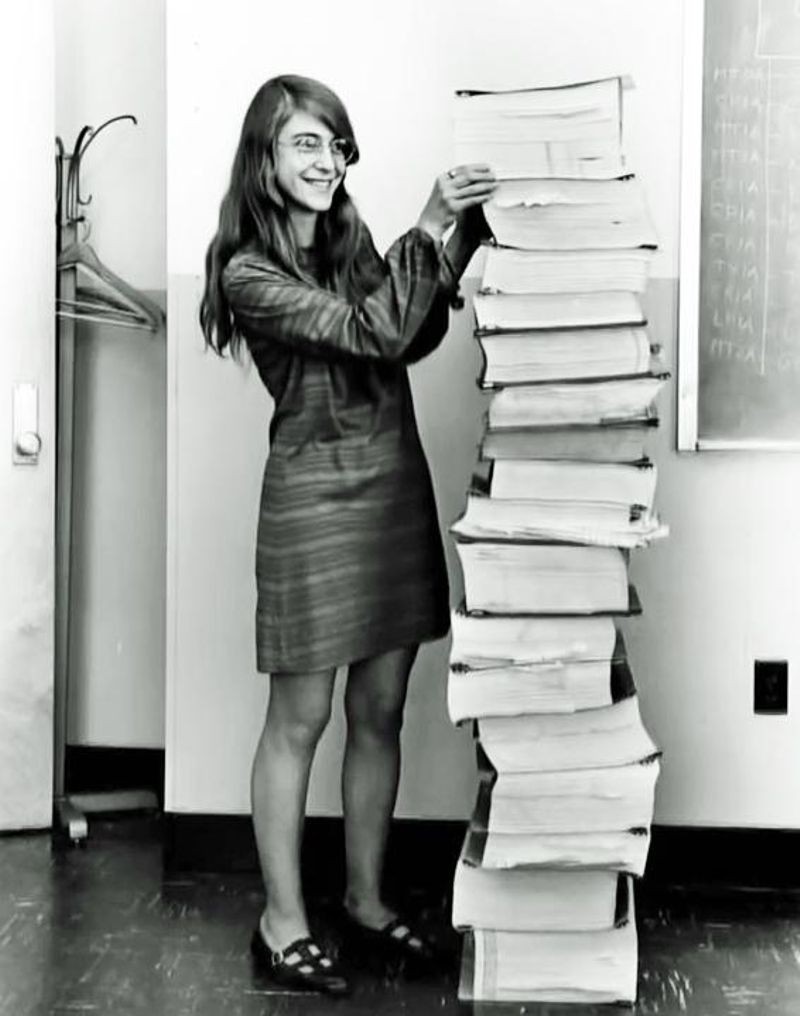Margaret Hamilton standing with the source code for the Apollo Guidance Computer.